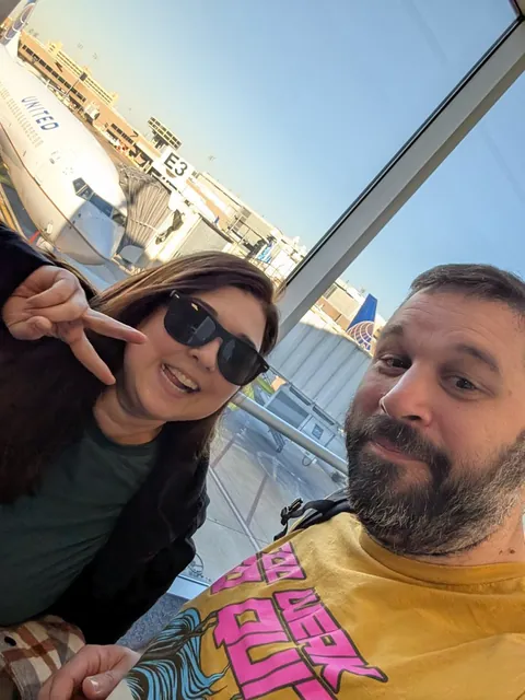 ashley closes it out with the peace sign and the shades on, gate E3 right over her shoulder. no turning back now, japan or bust.