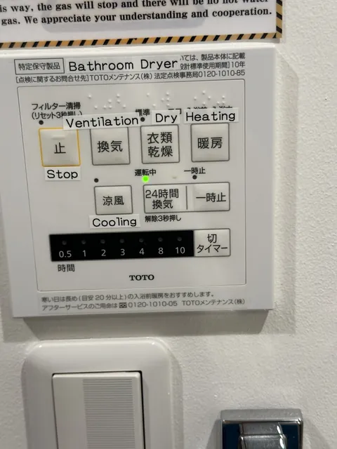 our airbnb bathroom ceiling can dry my laundry AND heat the room, but sure, let me decode 衣類乾燥 with a TOTO panel that came pre-Labeled in english AND braille while the notice up top calmly warns the gas might just shut off. that little green light is the only one here who knows what's going on.