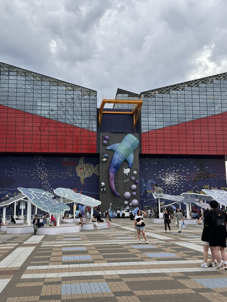 christina caught this shot of the MASSIVE whale sculpture diving through the osaka aquarium entrance - those solar panel umbrellas out front are pretty wild