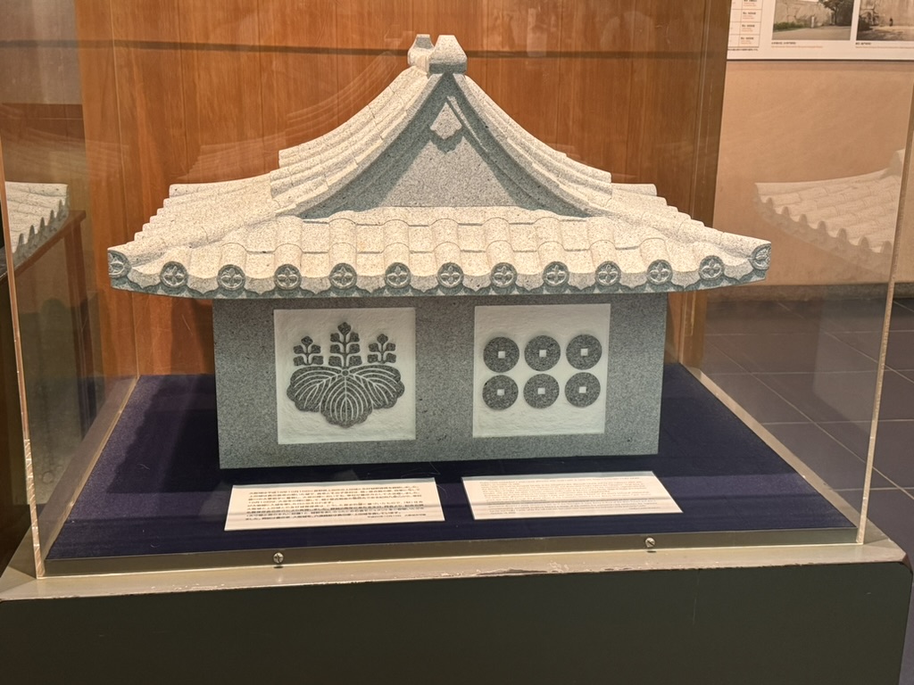 museum display at osaka castle showing an ornate roof tile with the tokugawa family crest and old japanese coins