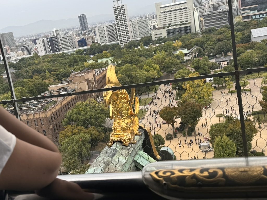 view from the top of osaka castle with daniel and christina checking out the MASSIVE golden shachihoko fish-tiger ornament that guards the roof