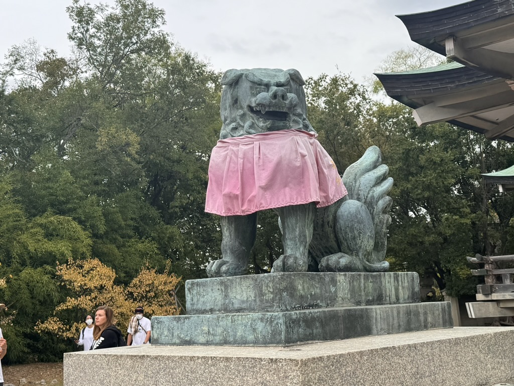 christina caught this komainu guardian at hokoku shrine rocking a pink skirt - because even fierce temple dogs need a fashion moment