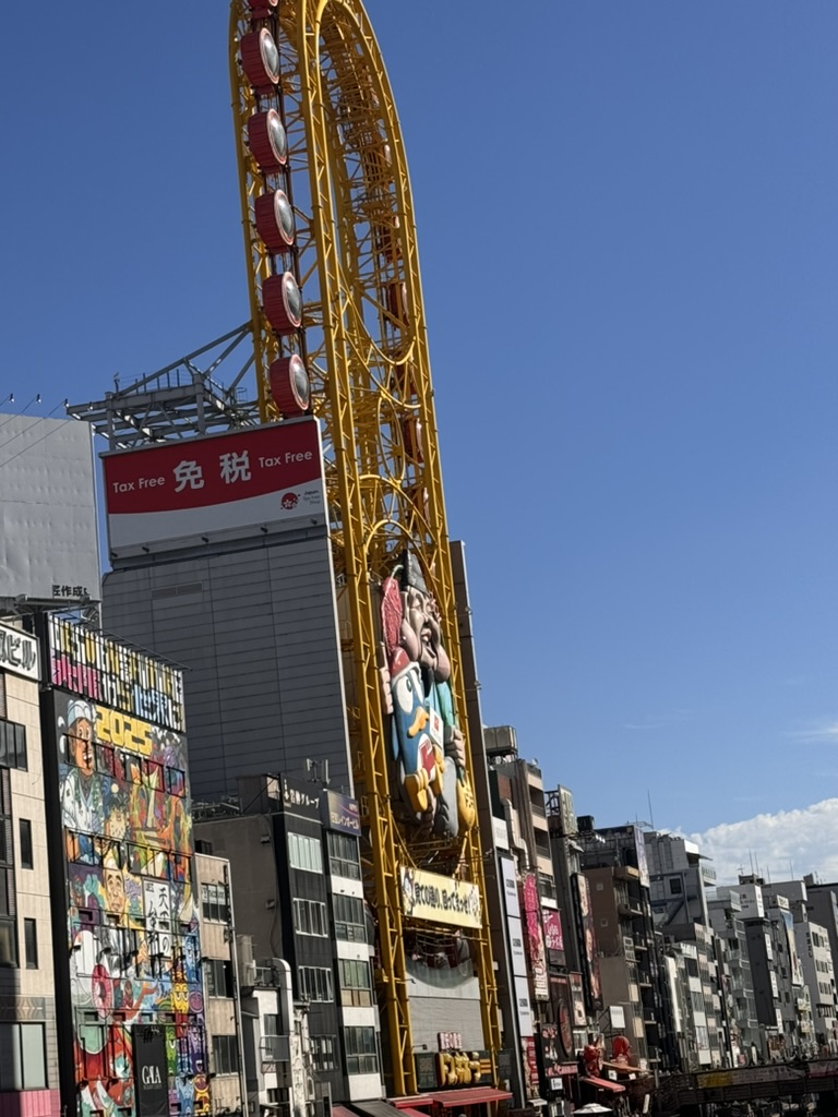 morning wandering through dotonbori - christina caught this shot of the iconic yellow ferris wheel against the wild urban canvas of osaka's entertainment district