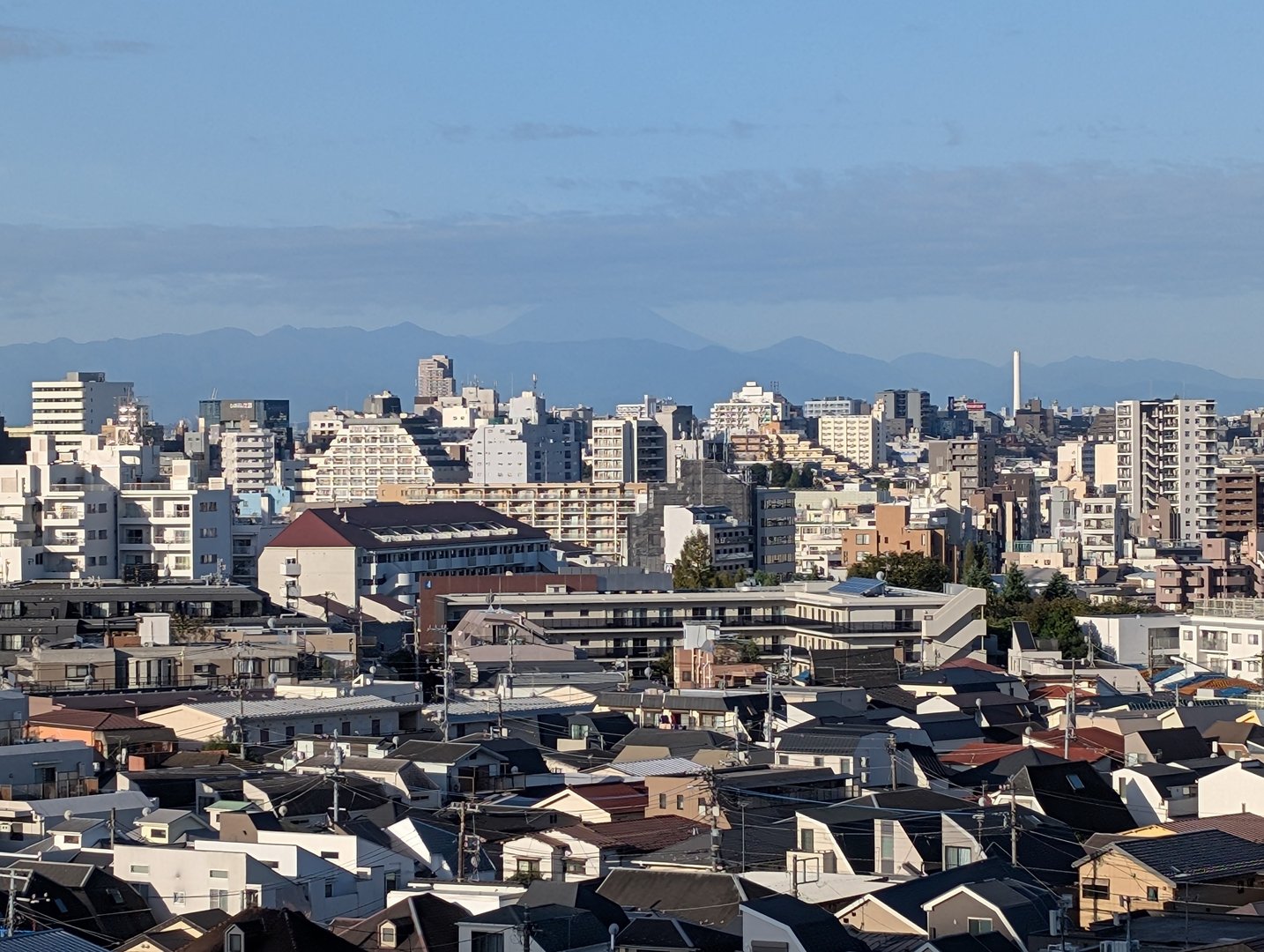 early morning view from our shinjuku airbnb with mt. fuji peeking through the haze behind the city skyline