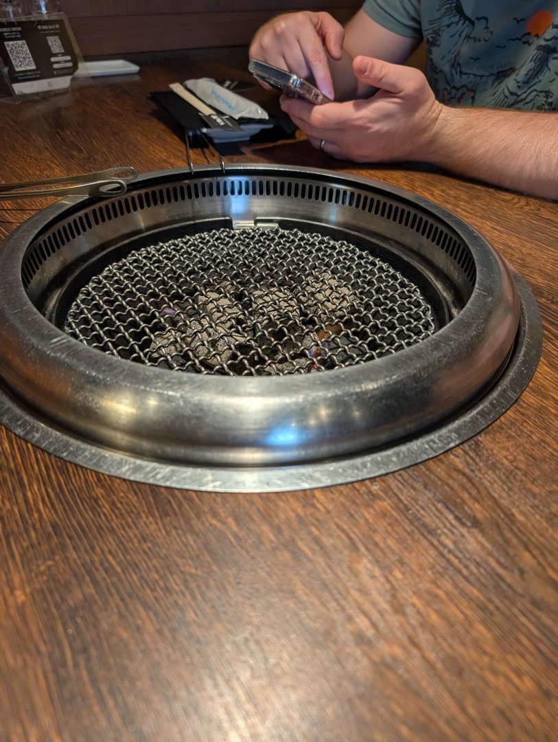 chuck checking his phone while waiting for our yakiniku to cook at this LEGIT spot in shinjuku. the smoke vent in the table is a next-level engineering feat