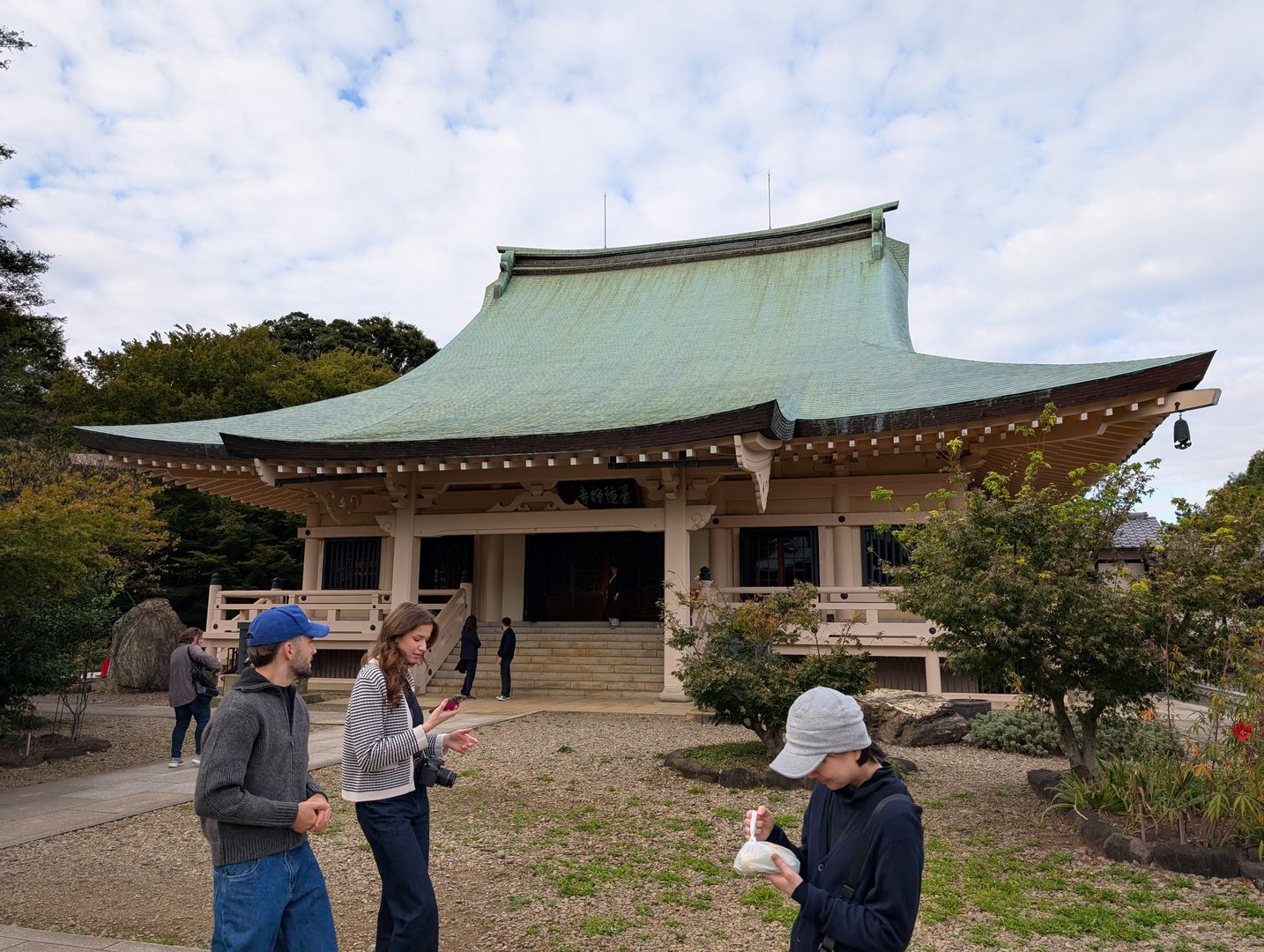 chuck and ashley checking their phones outside gotokuji temple in setagaya, where the famous maneki-neko (lucky cat) supposedly originated