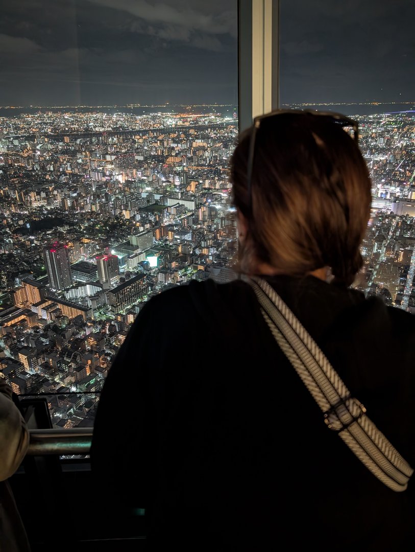 ashley taking in the MASSIVE scale of tokyo from the skytree observation deck at night. the city lights stretch as far as you can see.