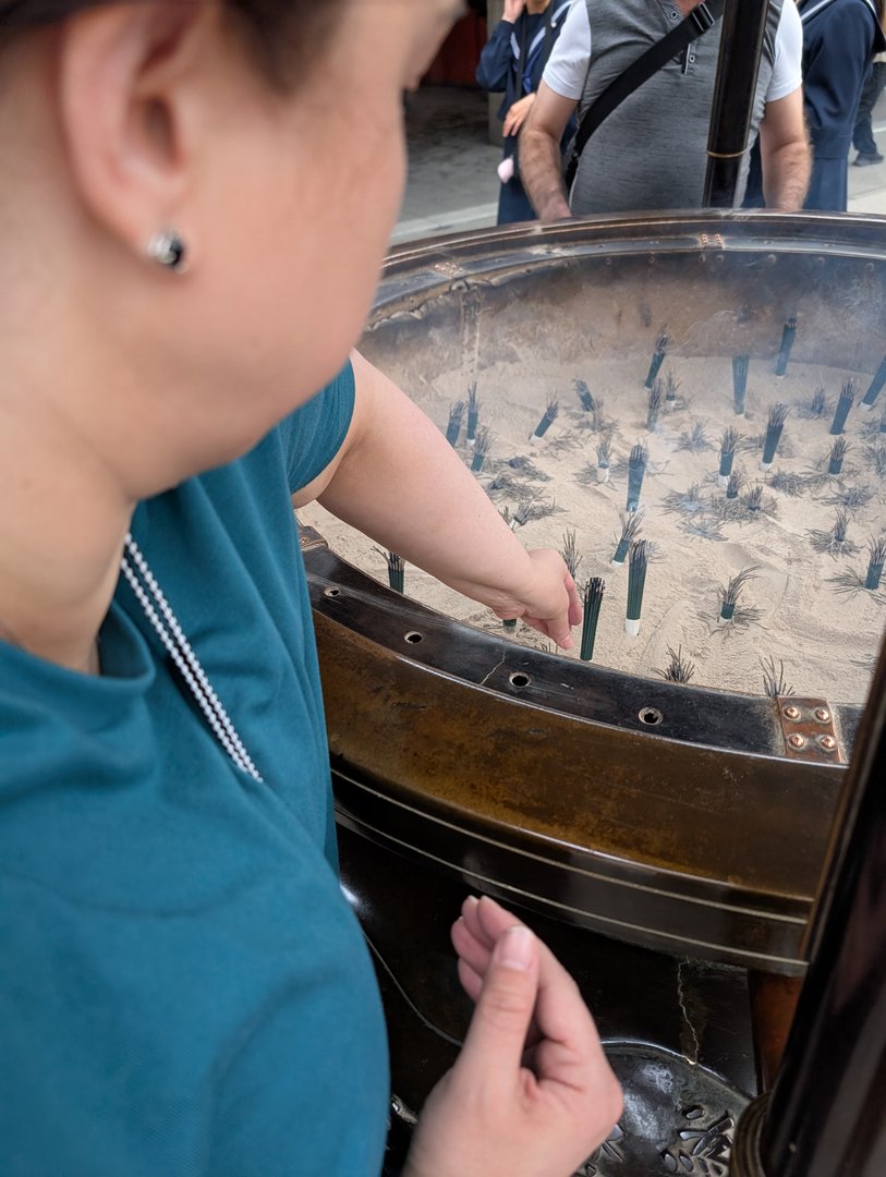 ashley lighting an incense stick at the sensoji temple's massive incense burner - the smoke is supposed to bring good health if you wave it over yourself