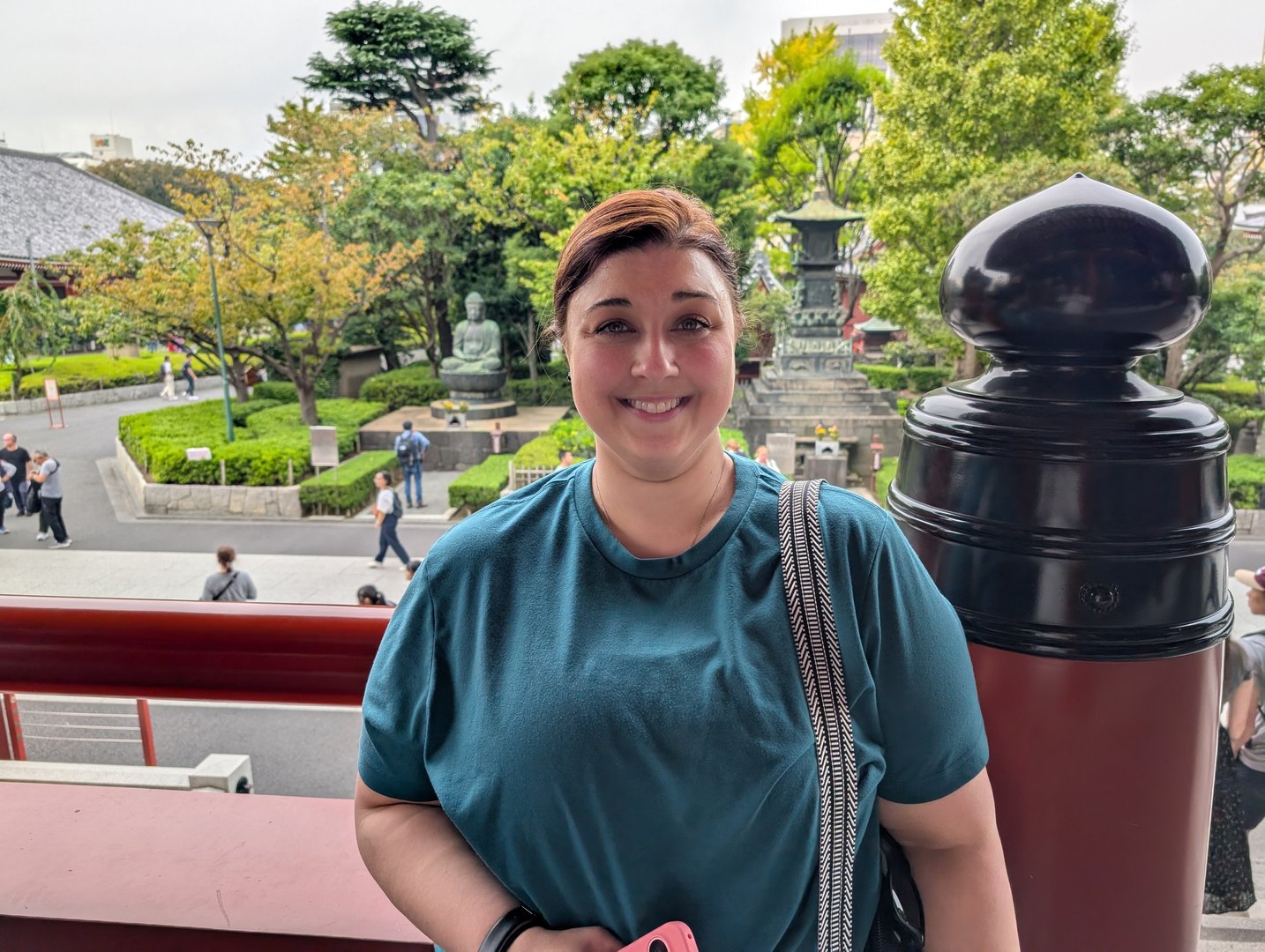 ashley taking a breather at the steps of sensoji temple, with the temple gardens and a bronze buddha statue in the background