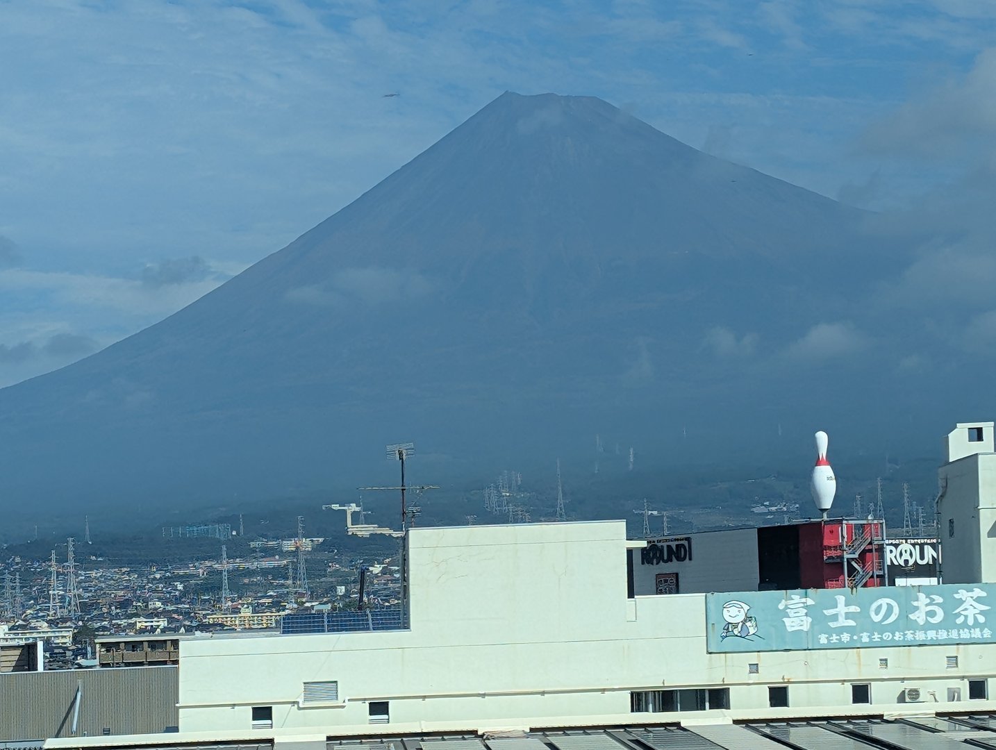 quick shot from the bullet train window passing through nagaizumi - mt. FUJI showing off with that perfect cone shape while a giant bowling pin watches from a rooftop