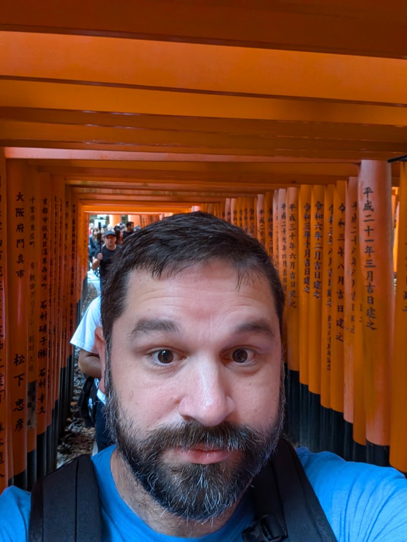 chuck's selfie in the iconic torii gate tunnel at fushimi inari, where thousands of orange gates wind up the sacred mountain