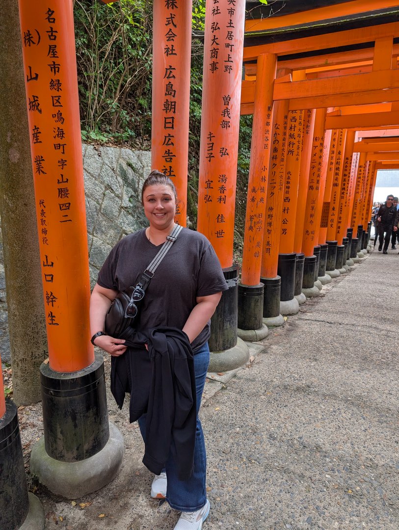 ashley pausing along the iconic torii gate path at fushimi inari shrine, where thousands of orange gates wind up mt inari