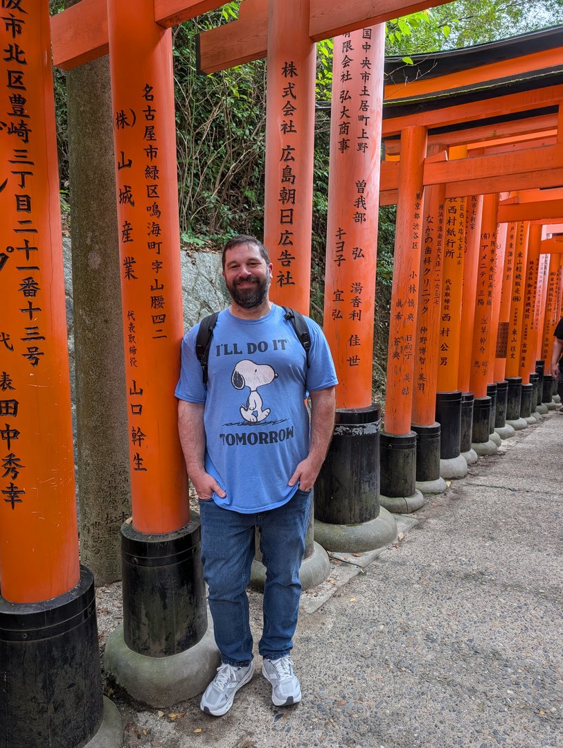 daniel taking a quick break among the endless torii gates at fushimi inari shrine, rocking his snoopy procrastination shirt