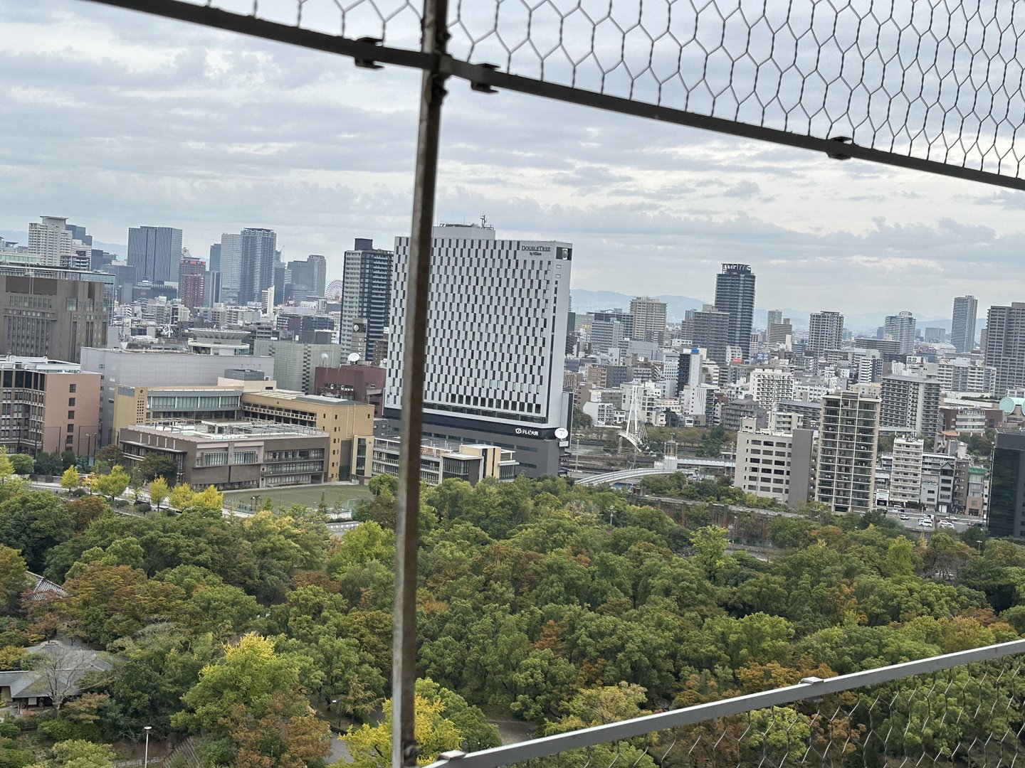 view from osaka castle observation deck showing how the city's modern skyline contrasts with the MASSIVE castle grounds below