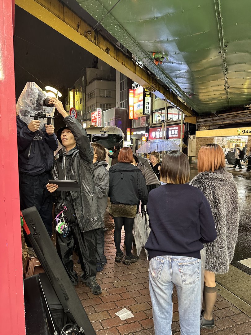 rainy night in shinjuku and the streets are still PACKED with people ducking under the train tracks with umbrellas